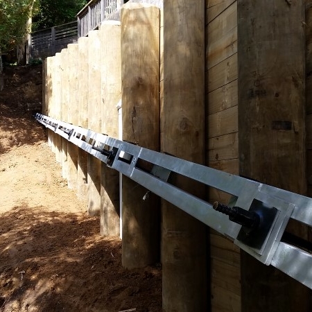 Tied-back timber pole retaing wall with steel waler and anchors